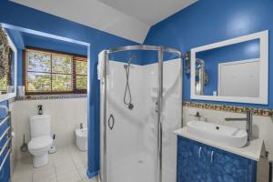 a blue bathroom with a shower and a sink at Cornwall Cottage in Merimbula +7 photos