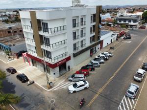 un bâtiment blanc avec des voitures garées dans un parking dans l'établissement Norte Hotel, à Taiobeiras
