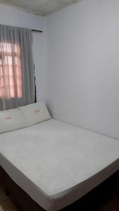a white bed in a room with a window at Hotel paraiso in Jataí