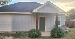 a white house with a door and two chairs at Simon's casitas! in McGregor