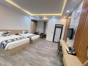 a hotel room with two beds and a flat screen tv at Sala Home Móng Cái in Móng Cái