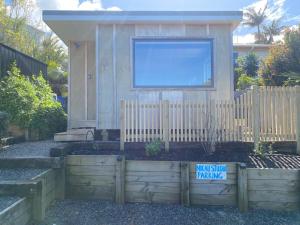 a tiny house with a fence in front of it at Nikau Studio in Raglan