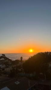 a sunset over the ocean with the sun setting at Bella vista al mar y cerca!! in El Quisco