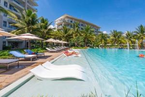 a pool at a resort with chairs and palm trees at Danang Ocean Resort & Spa Non Nuoc Beach Villas in Danang