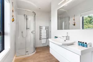 a white bathroom with a shower and a sink at Oceanview Oasis - Home & Apartment in Tairua +34 photos