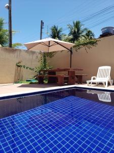 a swimming pool with a table and an umbrella at Pousada Mangata in Maragogi