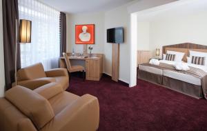 a hotel room with a bed and a couch and a chair at Fini-Resort Badenweiler in Badenweiler +30 photos