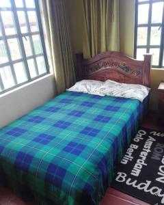 a bed in a bedroom with a blue and green blanket at POSADA VILLA DEL ROSARiO in Sutamarchán