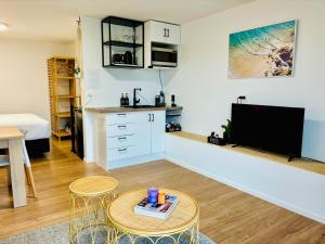 a living room with a kitchen and a table and a tv at Breezy Ocean - The perfect getaway in Mount Maunganui