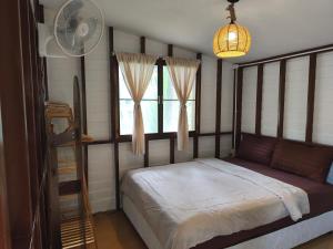 - une chambre avec un lit, un ventilateur et une fenêtre dans l'établissement Peace home kpg, à Baan Khai