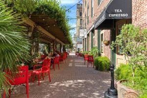 un patio con sedie rosse e persone sedute in un ristorante di Historic Downtown Galveston Loft with Balcony a Galveston