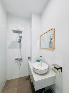 a white bathroom with a sink and a mirror at Ivory Blue Ninh Chử in Tan An