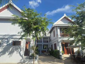 a white house with a tree in front of it at Asoca Hotel Luang Prabang in Luang Prabang