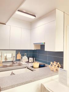 a kitchen with white cabinets and blue tiles at 달빛그리기Moonlight in Daegu