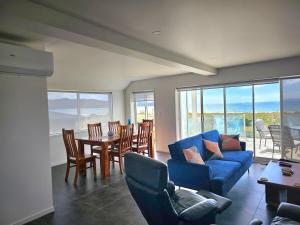 a living room with a blue couch and a table and chairs at Pyramid house in Karikari Peninsula