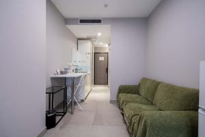 a living room with a green couch and a kitchen at Xihe Langyue Hotel Beijing Changying Tianjie Branch in Beijing