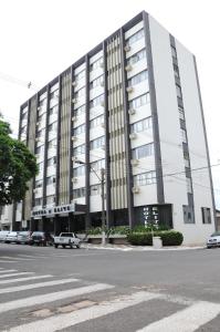 a large white building with cars parked in front of it at Hotel Elite in Paranavaí