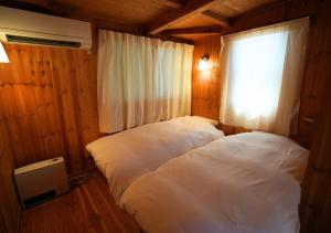 two white beds in a room with a window at 日は沈みまた昇る in Nirasaki