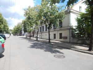 a street with a building and trees on the sidewalk at ROKO Apartments in Kaunas