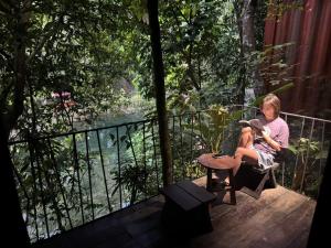 a woman sitting on a deck reading a book at YesHue Eco Waterfall Retreat in Hue