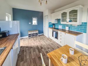 una cucina con pareti blu e tavolo in legno di Beachcroft Cottage a Aird Tong