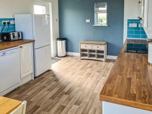 una cucina con elettrodomestici bianchi e pavimenti in legno di Beachcroft Cottage a Aird Tong