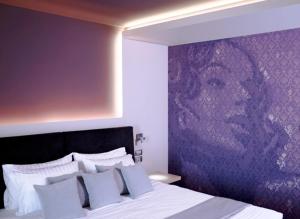 um quarto com uma cama com uma parede roxa em Tesoro Blu Hotel & Spa Adults Only em Skála Kefalonias
