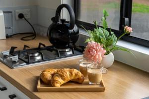 a tray of croissants and two glasses of coffee and a plate of bread at The Pink Lake Tiny House - 'Sakura' in Lochiel