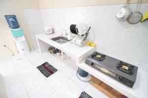 a kitchen with a sink and a stove at Omah Ati Guesthouse Syariah in Jarakan