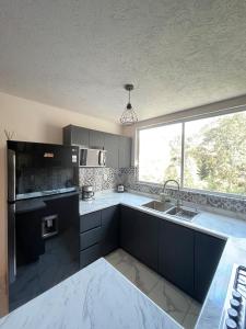 a kitchen with black cabinets and a sink and a window at Casa Karantani in Pátzcuaro