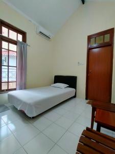a bedroom with a white bed and a window at Abadi Kos Harian in Ngabean