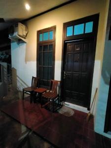 two chairs and a table in front of a door at Abadi Kos Harian in Ngabean