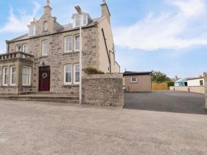 an old stone house with a red door at Crannoch Self Catering in Buckie