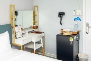 a bedroom with a desk and a refrigerator and a bed at Air diamond resort in Ban Nong Bon