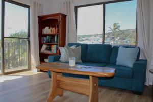 a living room with a blue couch and a coffee table at Doc's Place at Crescent Head in Crescent Head