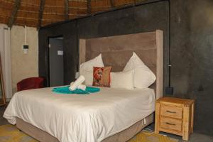 una camera da letto con un grande letto bianco e un comodino in legno di Imvomvo Country Lodge and Conference Center a Mount Ayliff