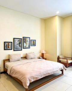 a bedroom with a large bed with three pictures on the wall at Alloro Boutique Hotel Pacitan in Pacitan