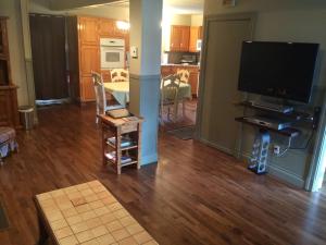 a living room with a large television and a kitchen at La Maison Clarence in Baie-Saint-Paul