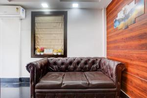 a brown leather couch in a room with a window at Super Collection O Biswa Bangla Kolkata Formerly Dream Palace in Kolkata