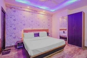 a bedroom with a white bed and a purple wall at Super Hotel O Vivaan Residency in Rohtak