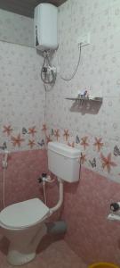La salle de bains est pourvue de toilettes et de fleurs sur le mur. dans l'établissement Vjay Shakti Homestay, à Gokarna
