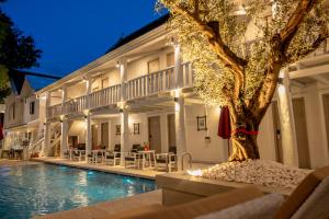 a swimming pool with a tree in front of a building at DownTown Hotel in Luang Prabang