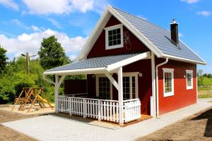 a red house with a gambrel roof at Agroturystyka - Stajnia Bursztynowa in Puck
