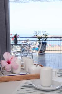 ジャルディーニ・ナクソスにあるCasa d'A..Mareのバルコニーに白いカップと花を飾ったテーブル