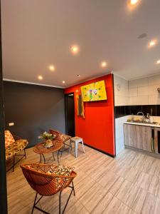 a room with a red wall and chairs and a kitchen at Cabaña familiar Huilo huilo in Choshuenco