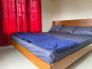 a bed in a bedroom with red curtains at Cosy Kalpetta Villa in Kalpetta +3 photos