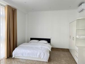 a white bedroom with a bed with white sheets at Màn Thầu Homestay in Ðình Loan