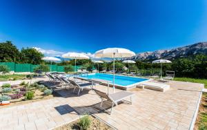 a swimming pool with chairs and umbrellas at Apartments Viktorija in Baška