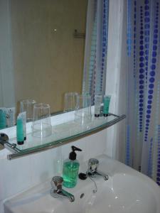 a bathroom with a sink with glasses and a mirror at The Bandstand in Nairn