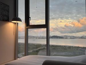 ein Schlafzimmer mit einem großen Fenster mit Blick auf das Wasser in der Unterkunft Grape Residence Hotel in Incheon
